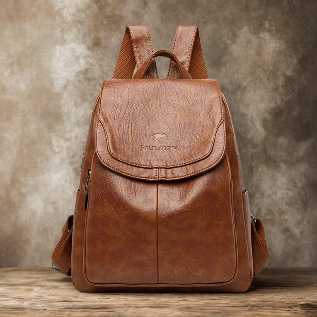 Brauner Leder-Rucksack auf Holztisch vor rustikalem Hintergrund. Stilvoller, vintage-inspirierter Rucksack für Damen und Herren. Ideal für Reisen.