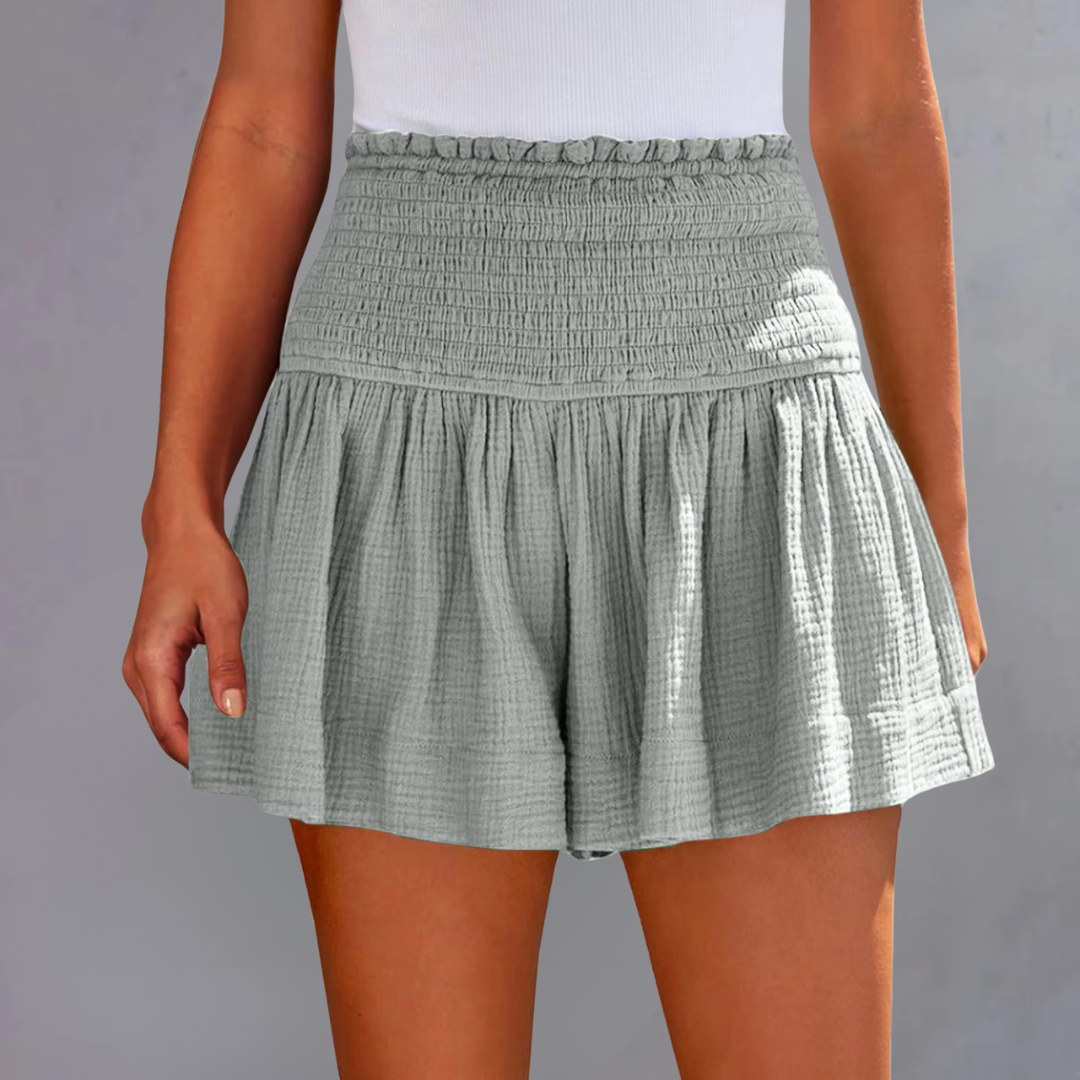 Frau trägt grauen, hoch taillierten, gerafften Rock aus Baumwolle. Sommermode, Damenbekleidung, stilvoller Freizeitlook.