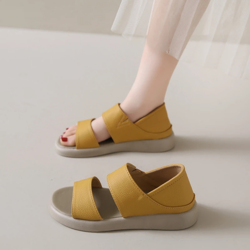 Gelbe Sandalen mit zwei Riemen, getragen von einer Person auf hellem Hintergrund. Modische Sommerschuhe, bequem und stilvoll für Damen.