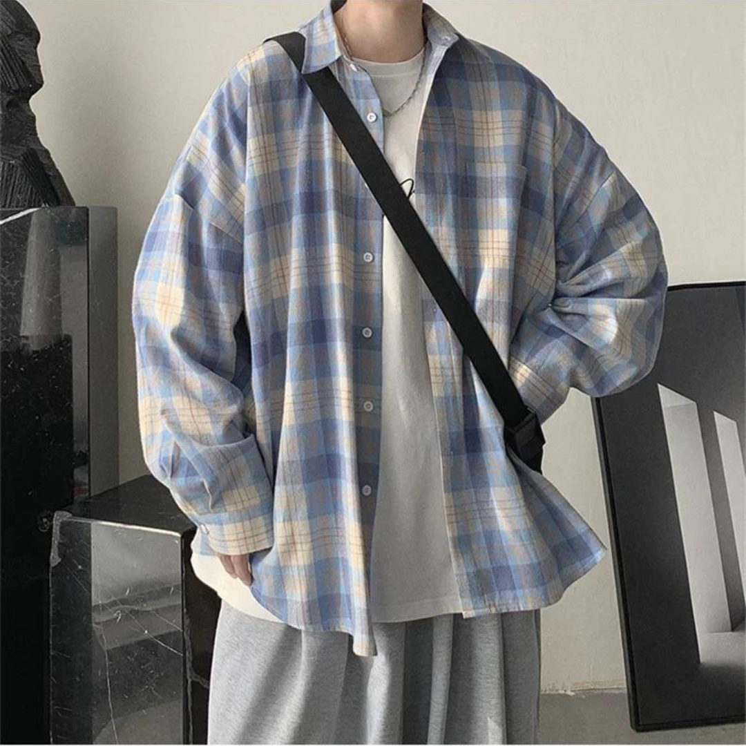 Person in kariertem Hemd und weißem T-Shirt, trägt schwarze Umhängetasche. Lässige Mode, urbaner Stil, trendige Freizeitkleidung.