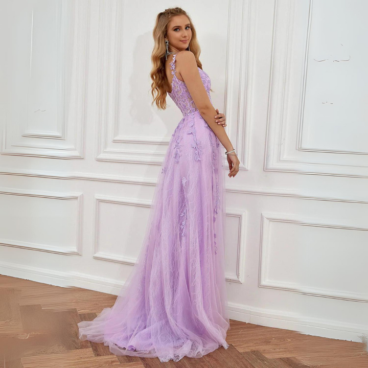 Frau in einem eleganten, lila Abendkleid mit Spitzenapplikationen, steht vor einer weißen Wand. Perfekt für Ball, Gala oder Hochzeit.