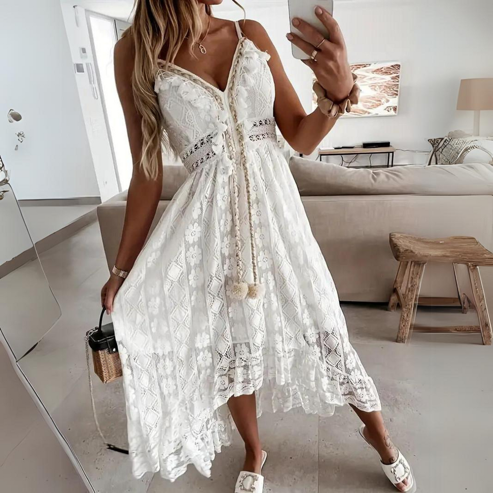 Frau in weißem Spitzenkleid posiert in modernem Wohnzimmer, hält eine kleine Tasche. Sommermode, elegantes Design, Freizeitkleidung.