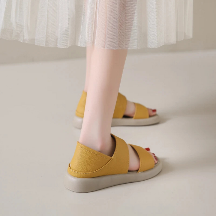 Frau trägt gelbe Sandalen mit beigem Absatz und weißem Tüllrock. Modische Sommerschuhe, Damenmode, bequeme Sandalen, stilvoller Look.