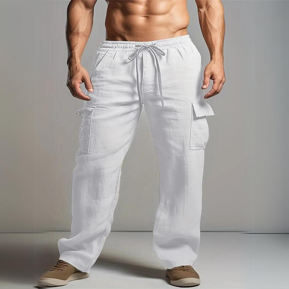 Mann in weißen Leinen-Cargohosen, muskulöser Oberkörper, beige Schuhe. Bequeme Sommermode, lässiger Stil, ideal für Freizeit und Strand.