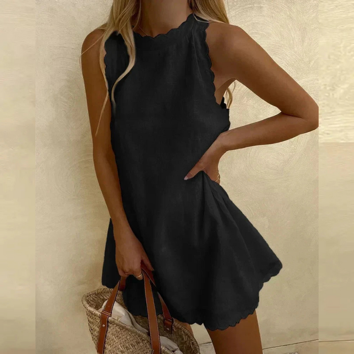 Frau in schwarzem Sommerkleid mit Wellensaum, hält eine Strohtasche. Modetrend, Sommeroutfit, Damenmode, elegantes Freizeitkleid.