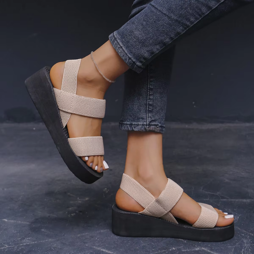Beige Sandalen mit Plateauabsatz, getragen von einer Person in Jeans. Modische Sommerschuhe, bequem und stilvoll für Damen.