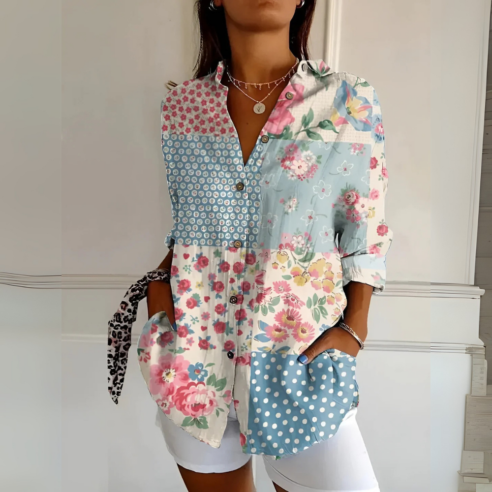 Frau trägt bunte Patchwork-Bluse mit Blumen- und Punktmuster, kombiniert mit weißen Shorts. Modetrend, lässiger Stil, Sommeroutfit.