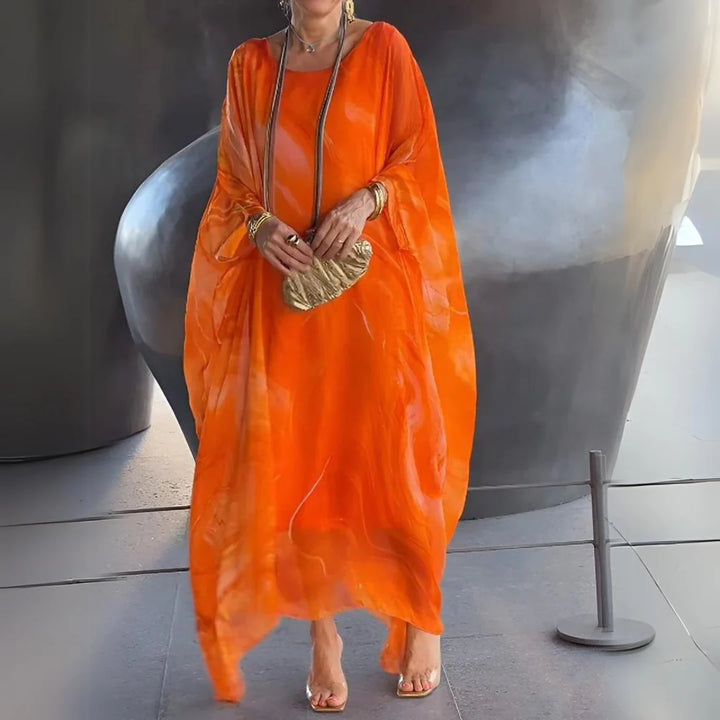 Elegante Frau in leuchtend orangefarbenem Kaftan mit goldener Clutch vor modernem, abstraktem Hintergrund. Modetrend, stilvolle Abendgarderobe.