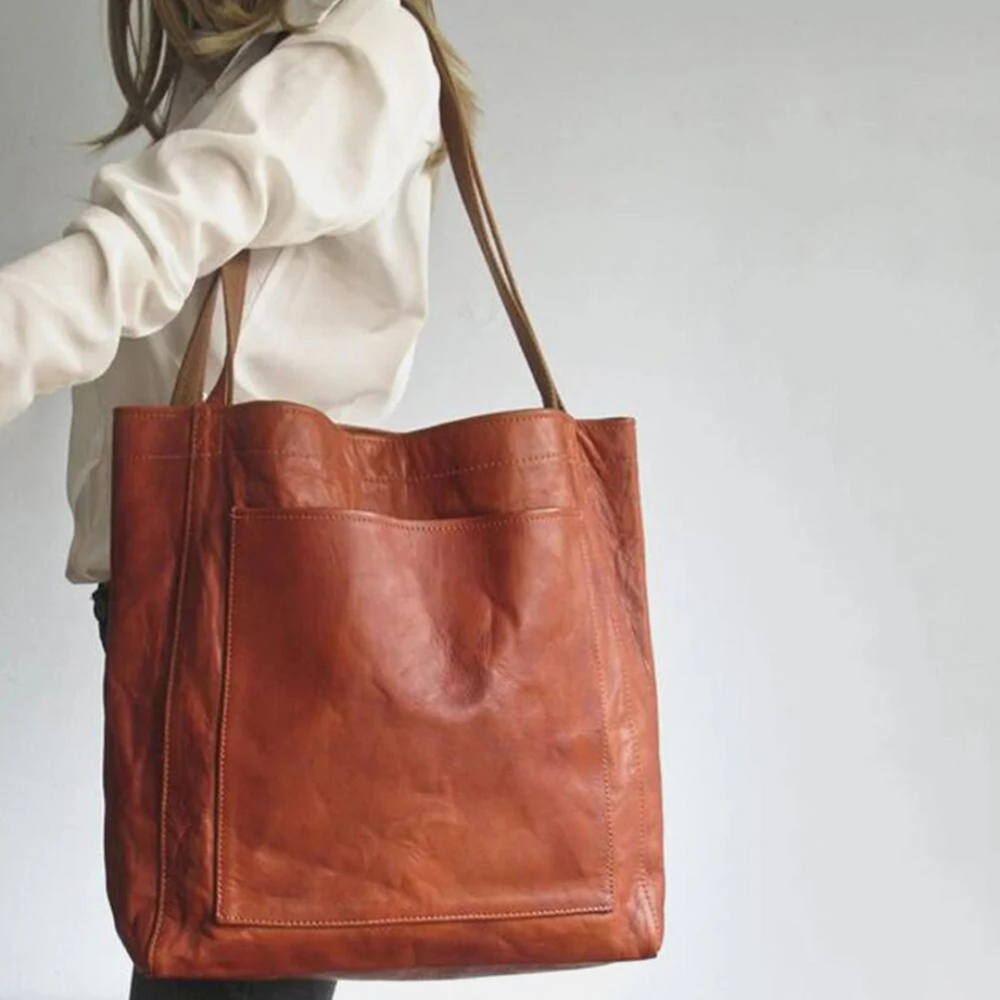 Frau mit großer brauner Ledertasche, Umhängetasche, modisches Accessoire, elegantes Design, ideal für Alltag und Büro, hochwertige Verarbeitung.