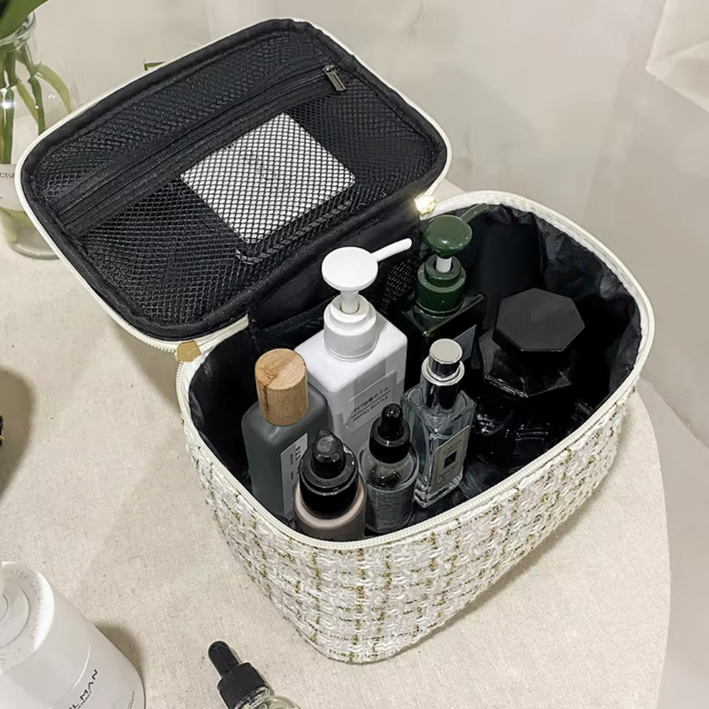 Kosmetiktasche mit Reißverschluss, gefüllt mit verschiedenen Pflegeprodukten und Parfümflaschen, auf einem Tisch. Ideal für Reisen und Organisation.