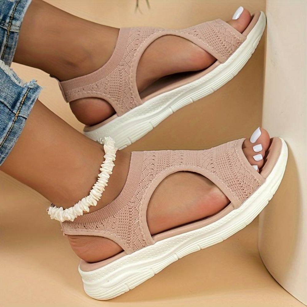 Damen Sandalen in Rosa mit Strickdesign und weißer Sohle, getragen mit Jeans und Fußkettchen. Bequeme Sommerschuhe für Frauen.
