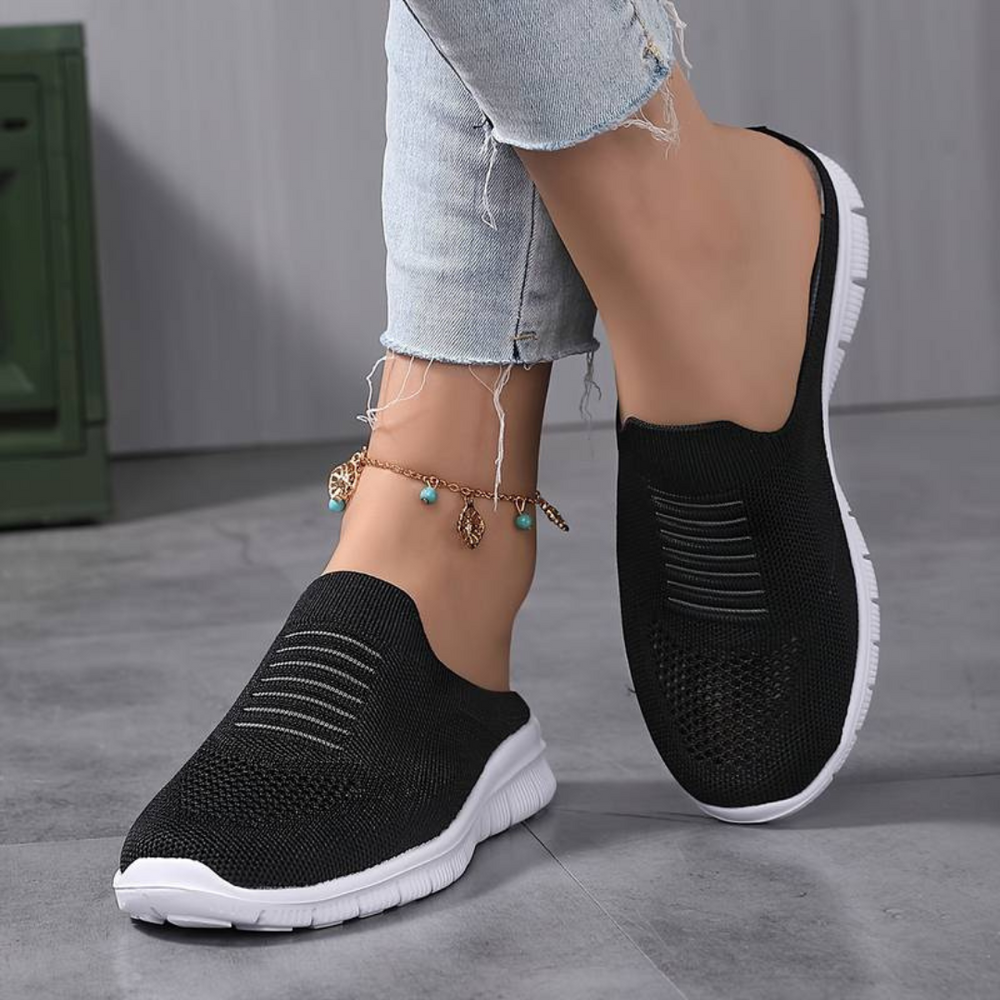 Schwarze Damen-Sneaker mit weißer Sohle, getragen mit hellblauen Jeans. Bequeme, atmungsaktive Freizeitschuhe für den Alltag.