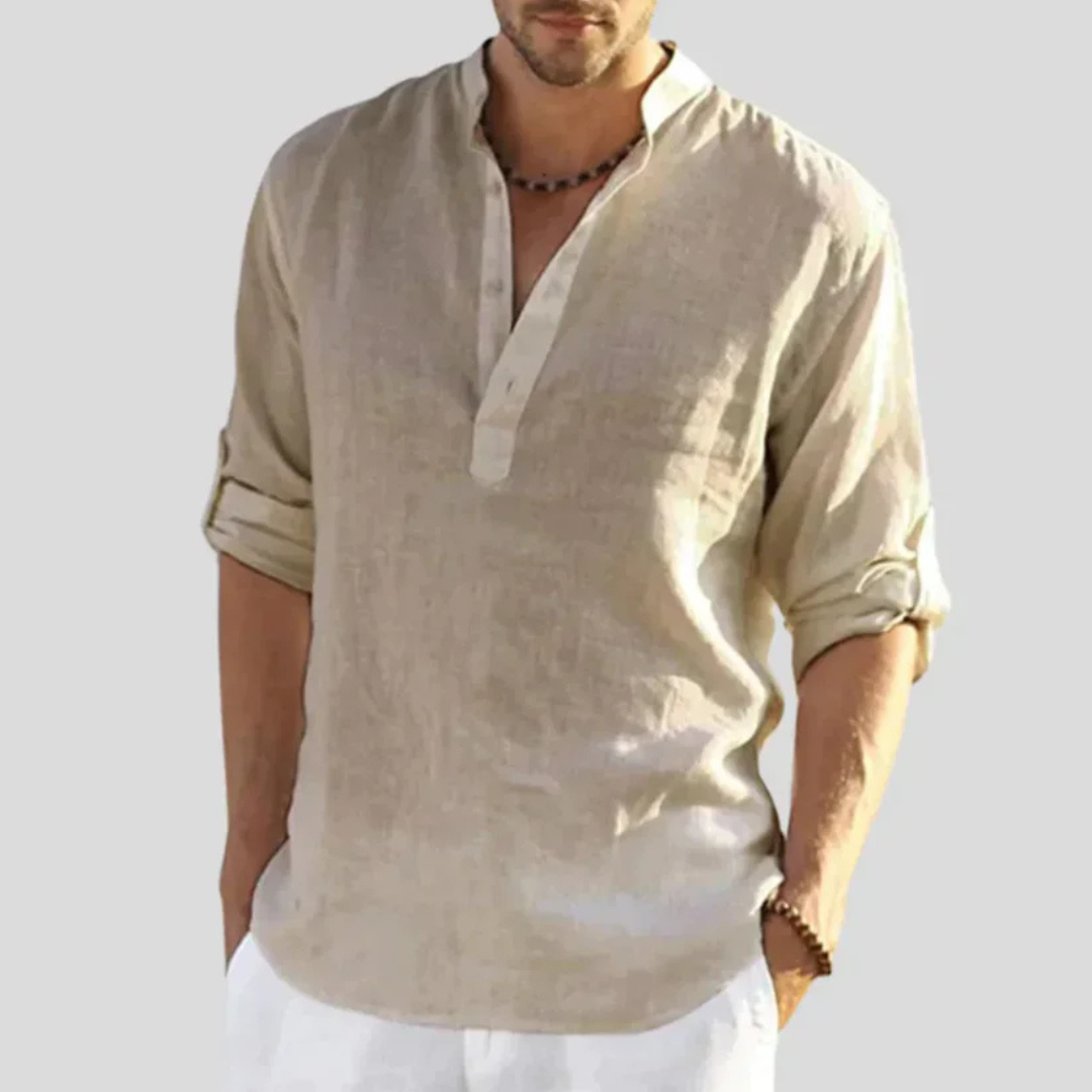 Mann trägt beiges Leinenhemd mit Stehkragen und hochgekrempelten Ärmeln. Sommermode, lässiger Stil, Herrenbekleidung, Freizeitlook.
