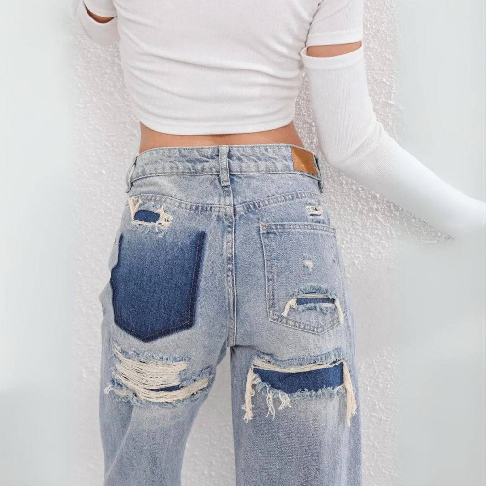 Frau in zerrissener Jeans und weißem Crop-Top, Rückansicht. Modetrend, Denim, Streetstyle, lässiger Look, moderne Kleidung.