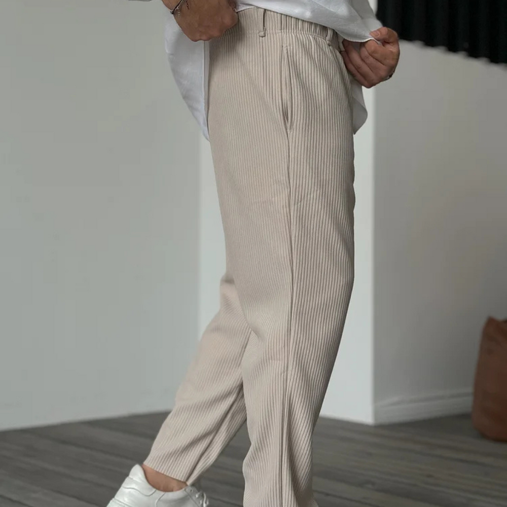 Beige Herren-Cordhose, modern geschnitten, kombiniert mit weißem Hemd und Sneakers. Stilvolle Herrenmode, ideal für Freizeit und Büro.