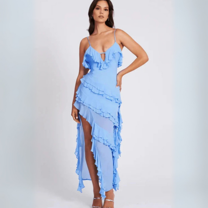 Frau in elegantem, blauem Rüschenkleid mit asymmetrischem Schnitt, Spaghettiträgern und hohen Absätzen. Perfekt für Abendmode und Sommerpartys.