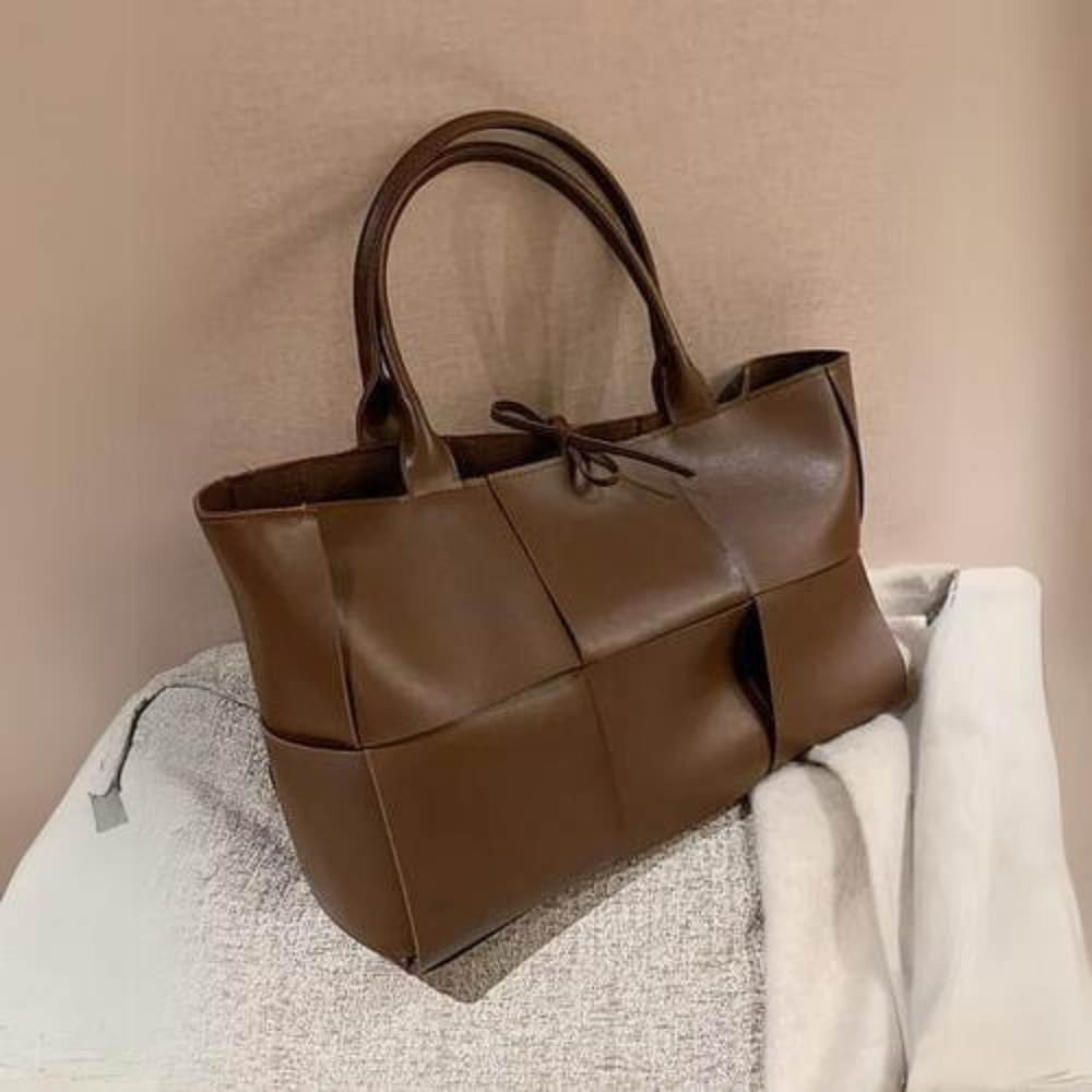 Braune Lederhandtasche mit geflochtenem Design auf beigem Hintergrund. Stilvolle Damenmode, luxuriöses Accessoire, elegantes Design.