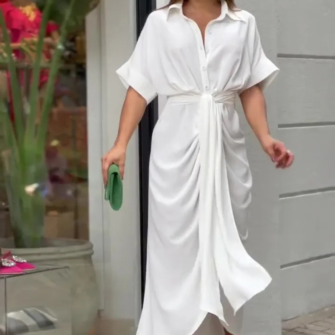 Elegantes weißes Hemdkleid mit Gürtel, getragen von einer Frau, die eine grüne Clutch hält. Perfekt für Sommermode und stilvolle Anlässe.