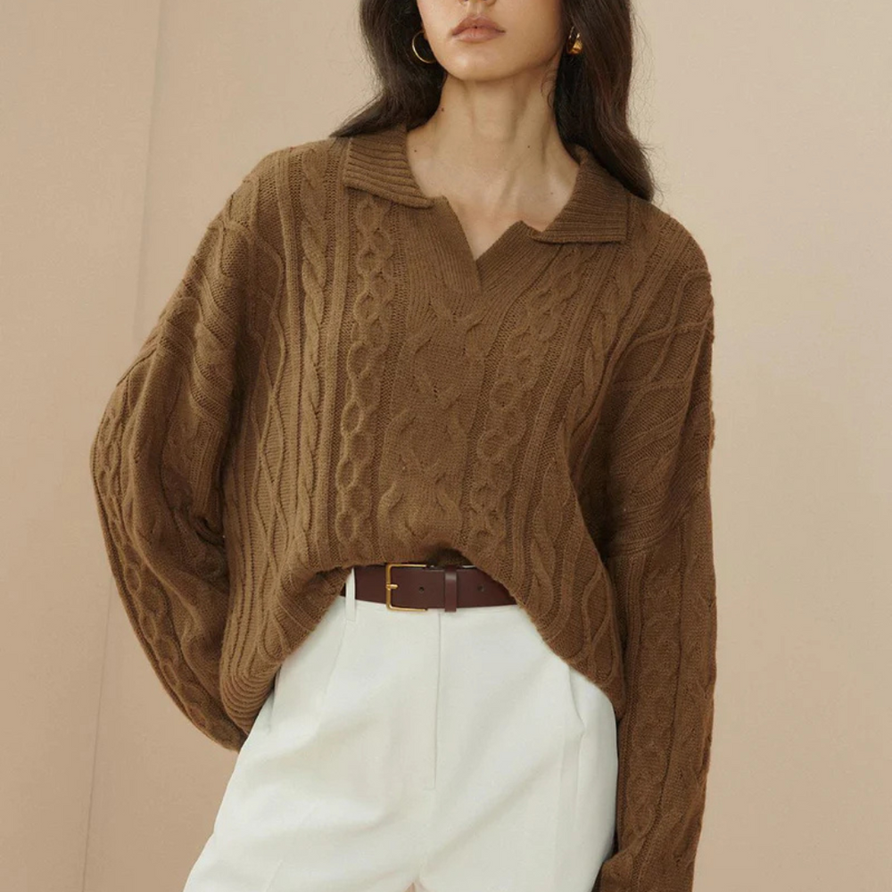 Brauner Strickpullover mit Zopfmuster, kombiniert mit weißer Hose und braunem Gürtel. Modetrend, Herbstmode, Damenbekleidung.