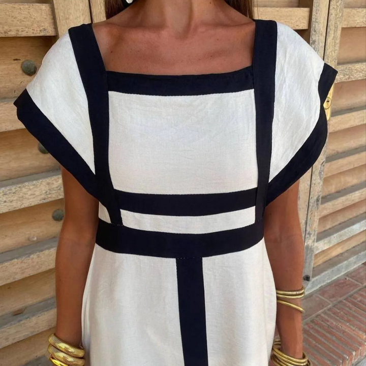 Frau in weißem Kleid mit schwarzen Streifen, quadratischer Ausschnitt, goldene Armreifen, modisches Sommeroutfit, elegantes Design.