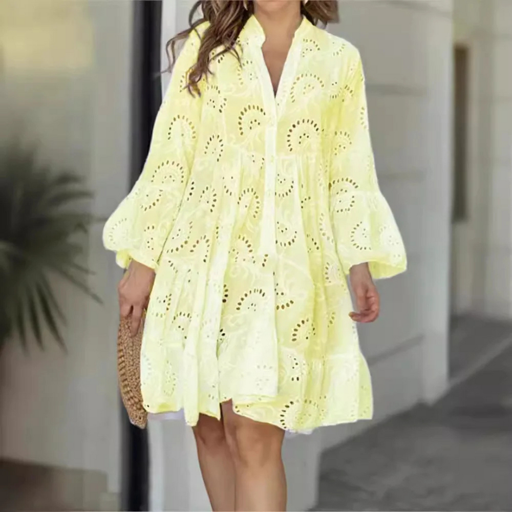 Frau in gelbem Sommerkleid mit Lochstickerei, hält eine Strohtasche. Perfekt für Sommermode, Freizeitkleidung, luftiges Design.