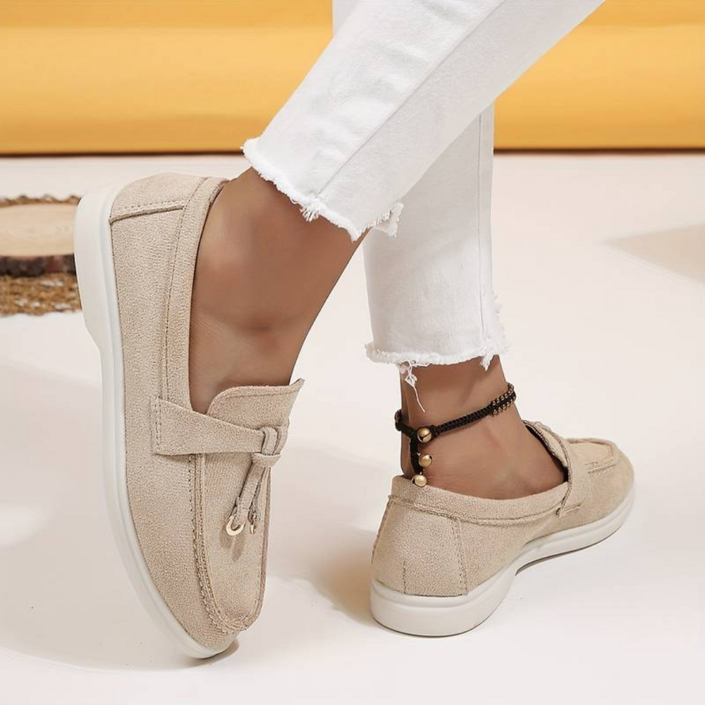 Damenbeige Mokassins aus Wildleder, kombiniert mit weißen Jeans. Bequeme Freizeitschuhe, ideal für den Alltag. Modetrend 2023.