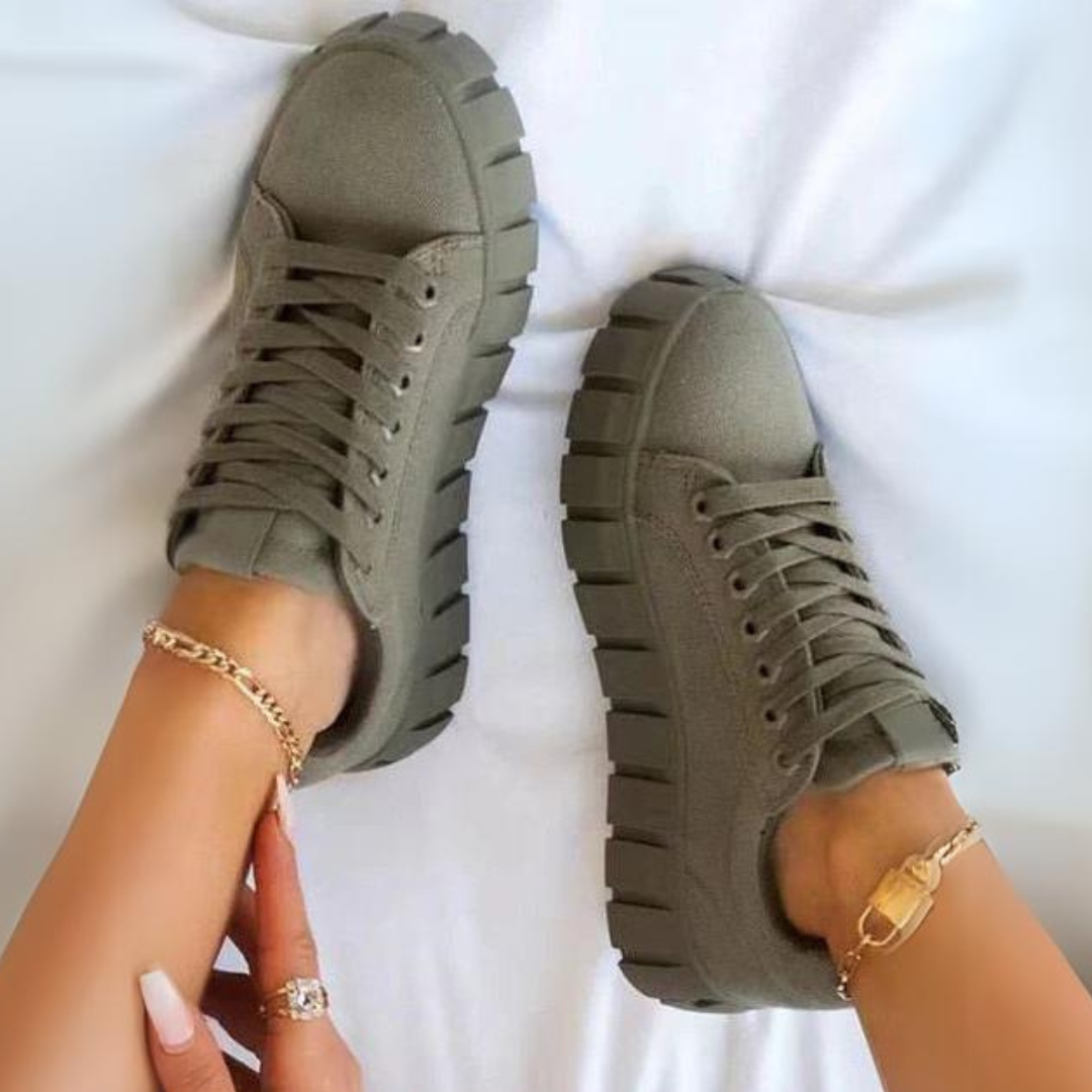 Damen Sneaker in Olivgrün mit dicker Sohle, getragen mit goldenen Fußkettchen. Modische Schuhe, ideal für Freizeit und Streetwear.