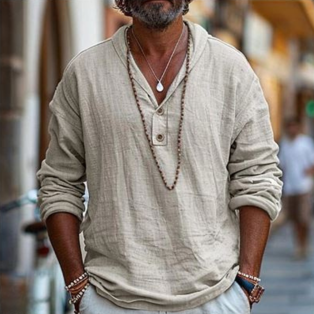 Mann in beiger Leinenbluse mit Holzperlenkette, lässiger Stil, Stadtstraße im Hintergrund. Mode, Herrenbekleidung, urbaner Look.