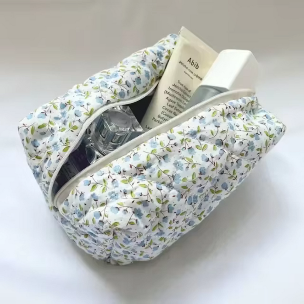 Blumige Kosmetiktasche mit Reißverschluss, gefüllt mit Parfümflasche, Creme und Lotion. Praktisch für Reisen und tägliche Pflege.