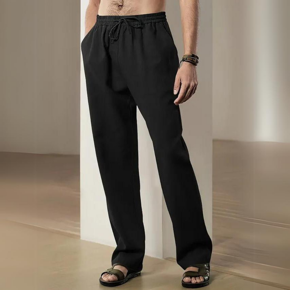 Mann trägt schwarze Jogginghose und Sandalen, steht in modernem Raum. Bequeme Freizeitmode, Herrenbekleidung, lässiger Stil.