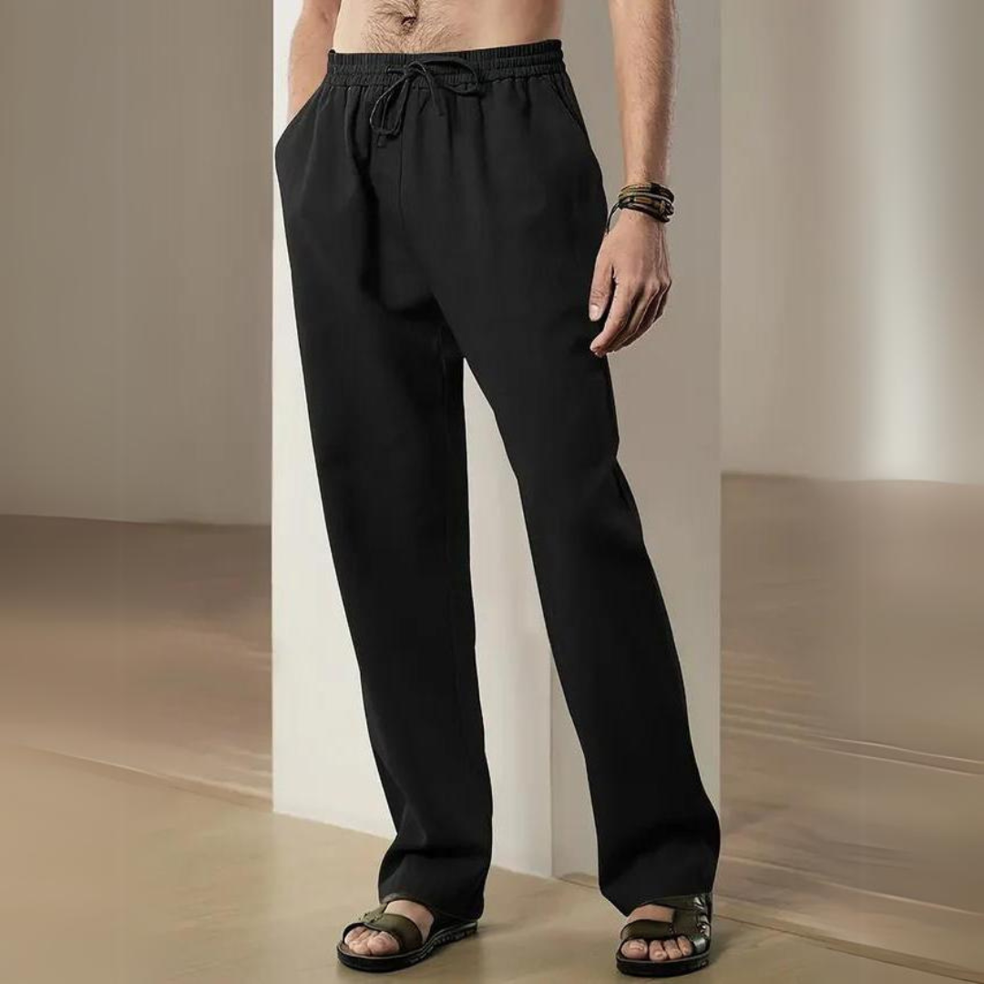 Mann trägt schwarze Jogginghose und Sandalen, steht in modernem Raum. Bequeme Freizeitmode, Herrenbekleidung, lässiger Stil.