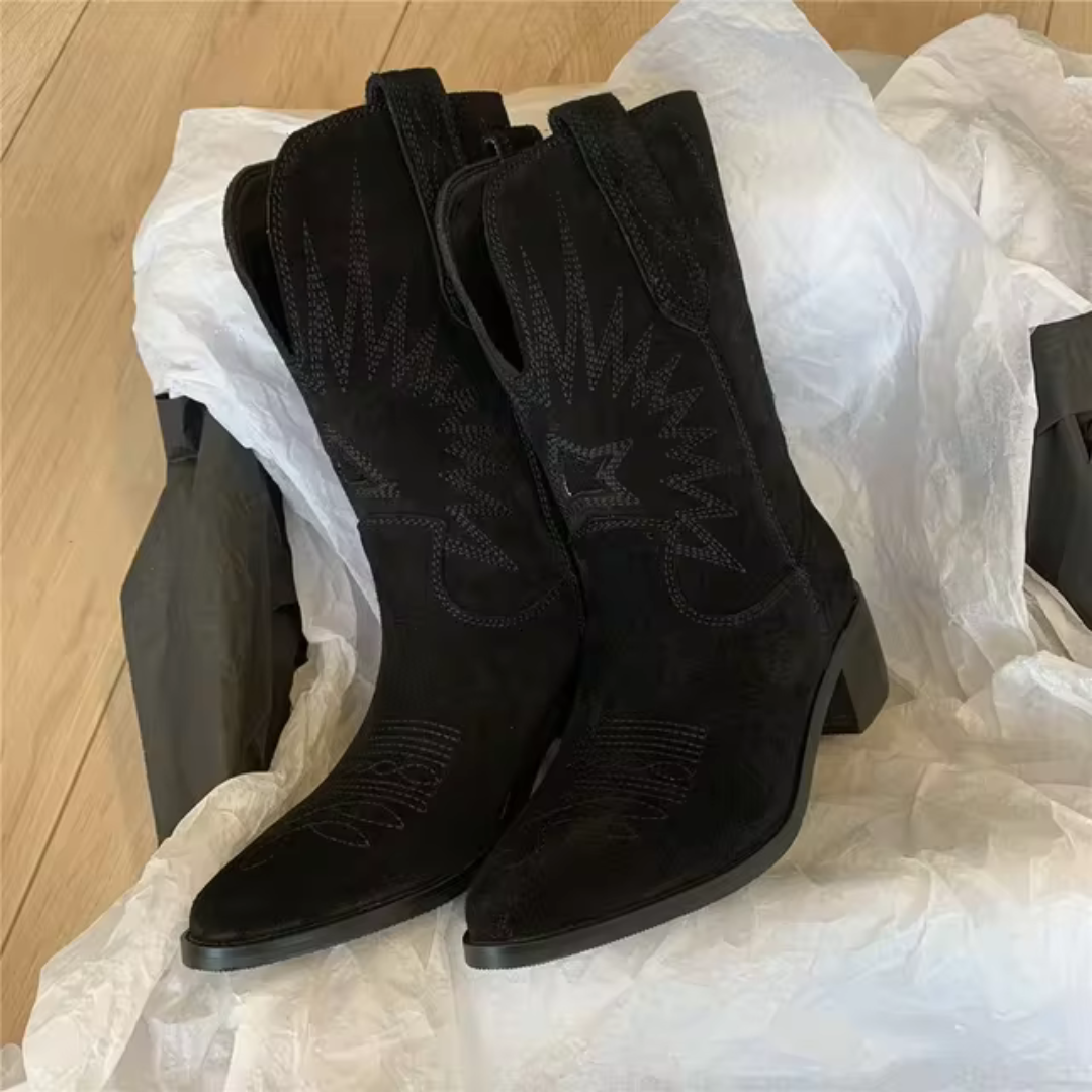 Schwarze Cowboy-Stiefel aus Wildleder mit Stickerei, auf weißem Papier präsentiert. Modische Westernstiefel, ideal für trendige Outfits.