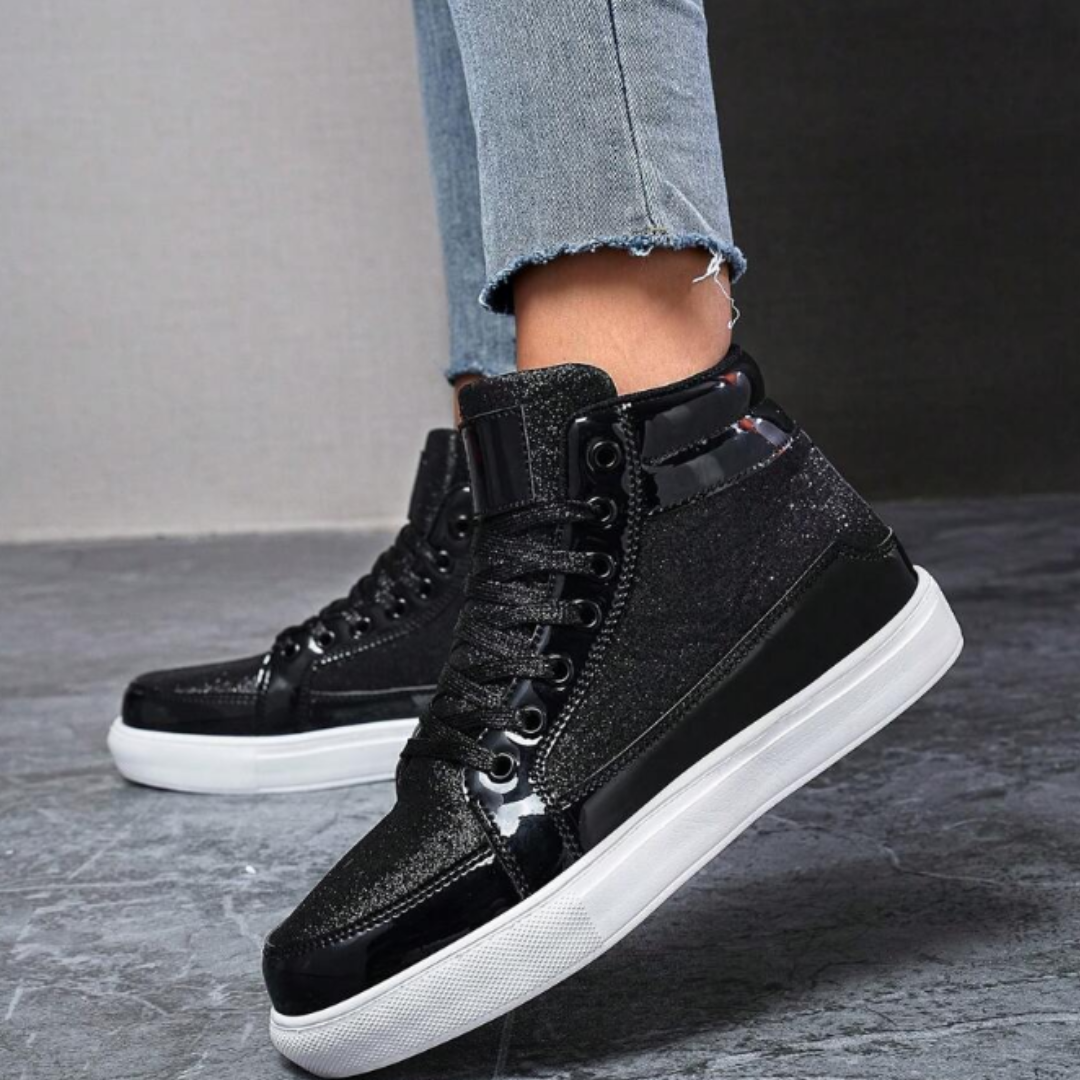 Schwarze Glitzer-Sneaker mit weißer Sohle, getragen von Person in blauen Jeans. Modische Damen-Schuhe, ideal für urbanen Streetstyle.