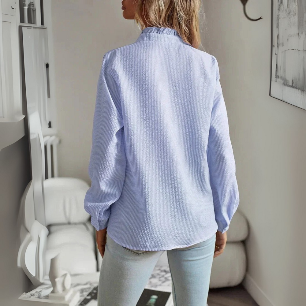 Frau in hellblauer Bluse und Jeans steht in modernem Wohnzimmer. Stilvolle Mode, Freizeitkleidung, Innenarchitektur, skandinavisches Design.