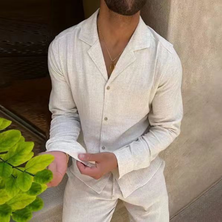 Mann in beigem Leinenanzug mit offenem Kragen, hält Ärmel. Stilvolle Herrenmode, Sommeroutfit, elegantes Design.