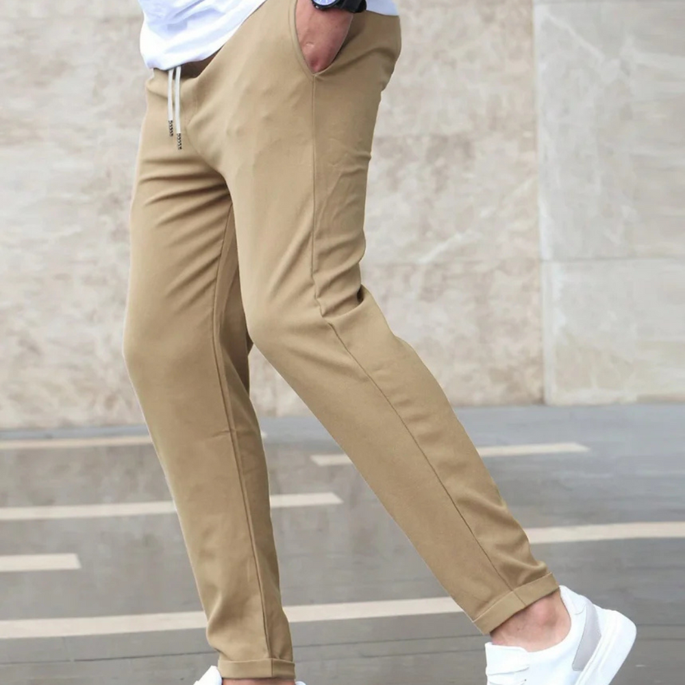Beige Jogginghose für Herren, kombiniert mit weißen Sneakern. Bequeme Freizeitmode, ideal für sportliche Aktivitäten und lässige Outfits.