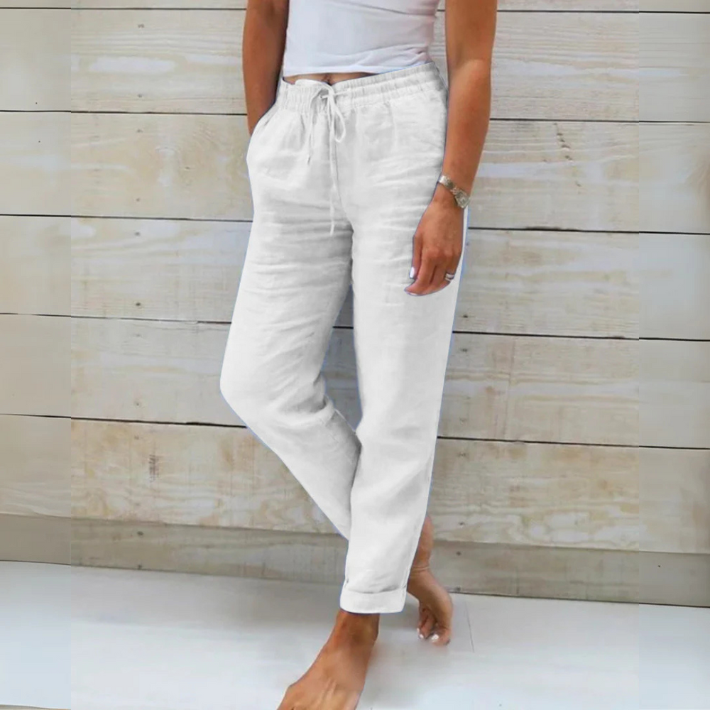 Weiße Leinenhose Damen, lässig, mit Kordelzug, Taschen, bequem, ideal für Sommermode, Freizeitlook, vor hellem Holzhintergrund.