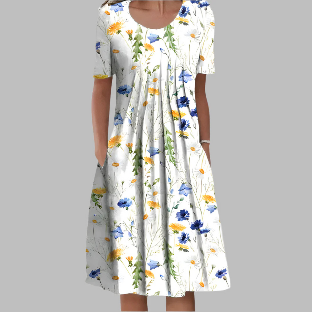 Frau in weißem, geblümtem Sommerkleid mit blauen und gelben Blumen, knielang, kurzärmelig, vor grauem Hintergrund. Modetrend, Damenmode, Sommerkleid.