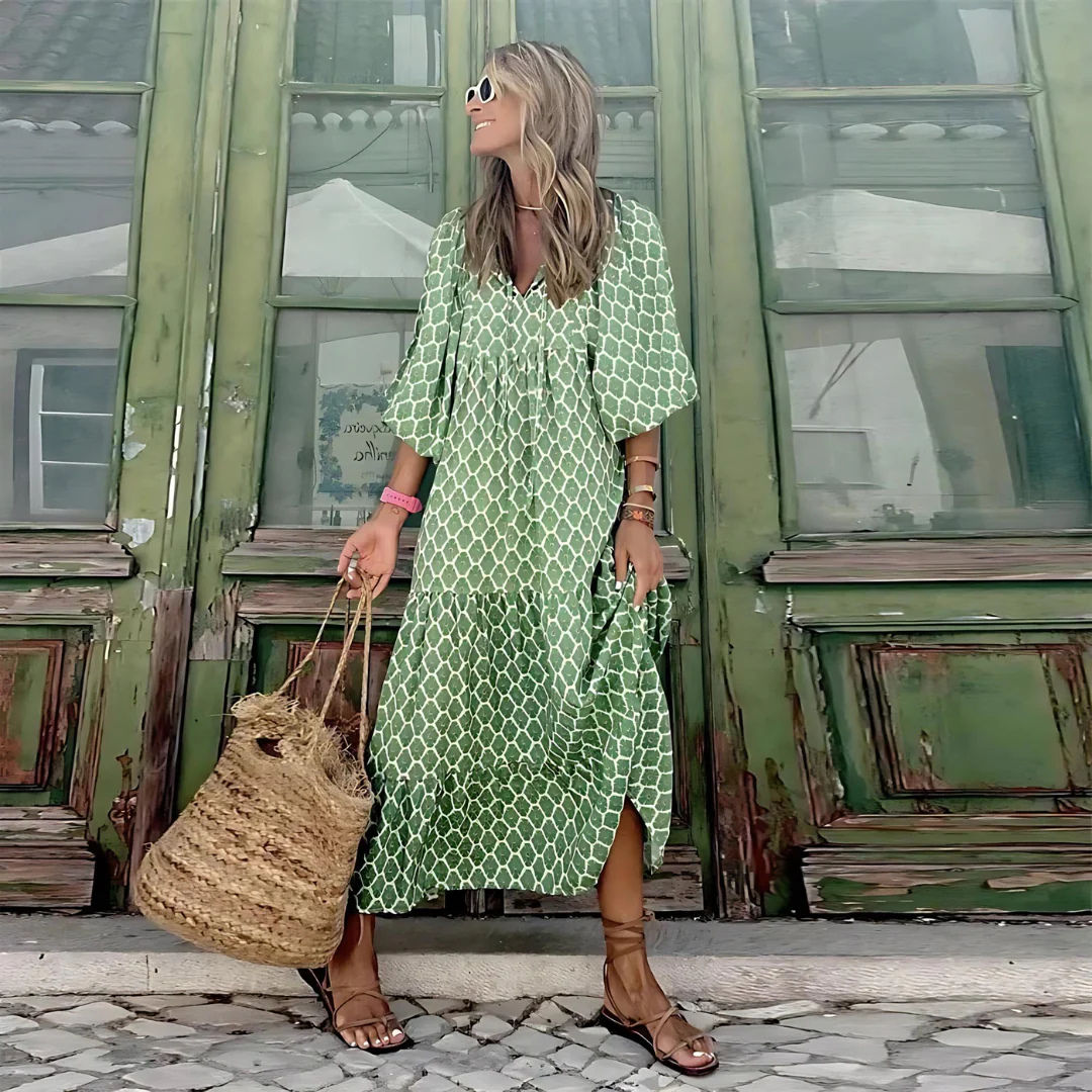 Frau in grünem Sommerkleid vor antiker Holztür, trägt Strohtasche und Sonnenbrille. Modetrend, Sommermode, Boho-Stil, lässiger Look.