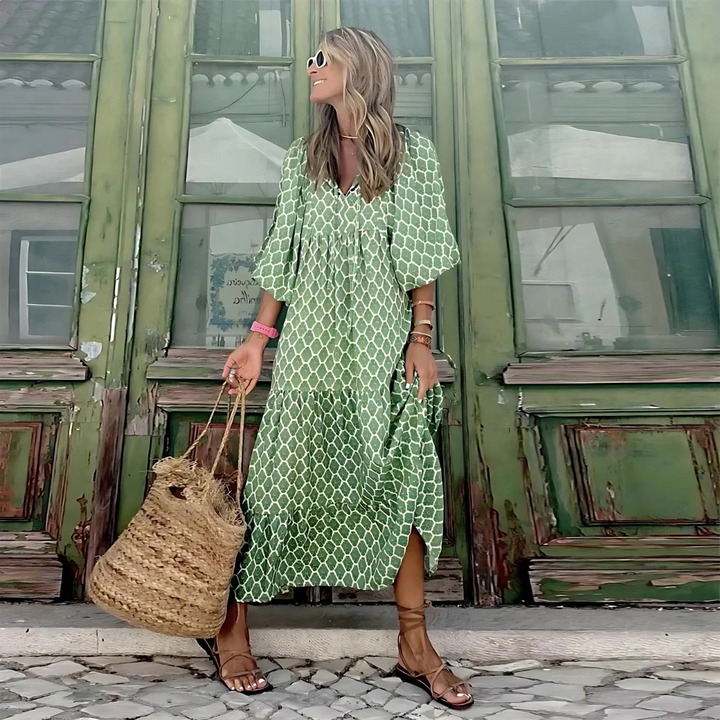 Frau in grünem Sommerkleid vor antiker Holztür, trägt Strohtasche und Sonnenbrille. Modetrend, Sommermode, Boho-Stil, lässiger Look.