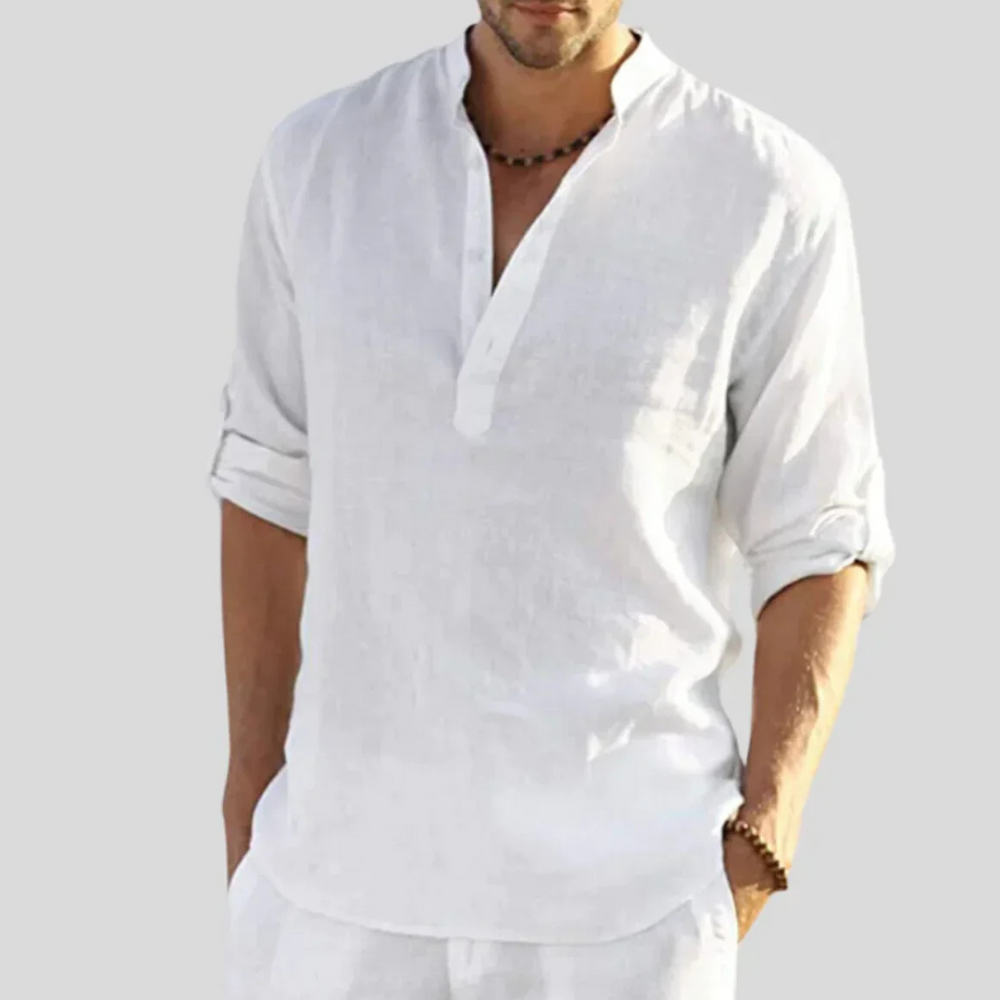 Mann in weißem Leinenhemd mit Stehkragen und hochgekrempelten Ärmeln, lässiger Sommerlook, ideal für Strandmode und Freizeitkleidung.