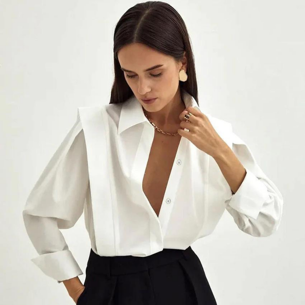 Frau in eleganter weißer Bluse mit tiefem Ausschnitt und schwarzen Hosen, trägt goldene Ohrringe und Kette, modisches Outfit, minimalistischer Stil.