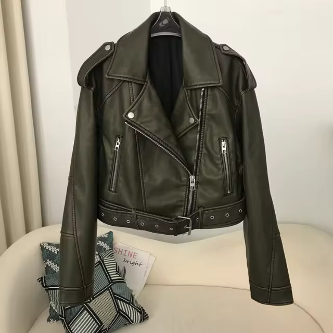 Schwarze Lederjacke mit Reißverschlüssen und Gürtel, hängend auf einem Kleiderbügel. Perfekt für modische Herbst- und Winteroutfits.