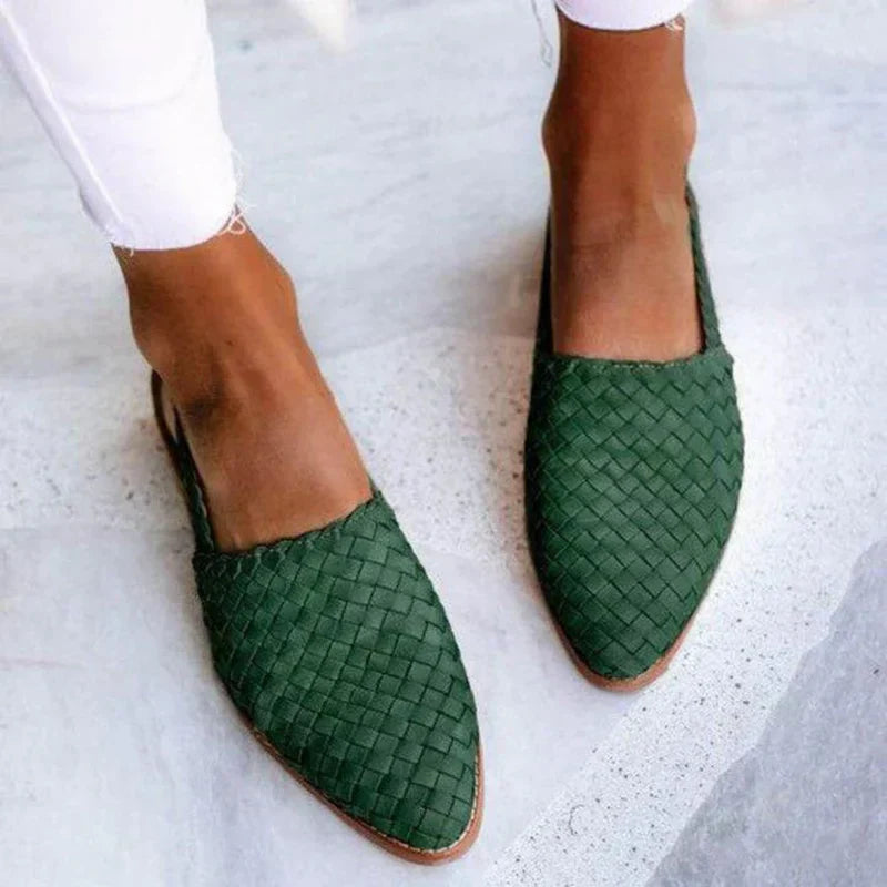 Grüne geflochtene Damen-Slipper aus Leder, getragen mit weißen Jeans. Modische Sommerschuhe, bequem und stilvoll für Freizeitkleidung.