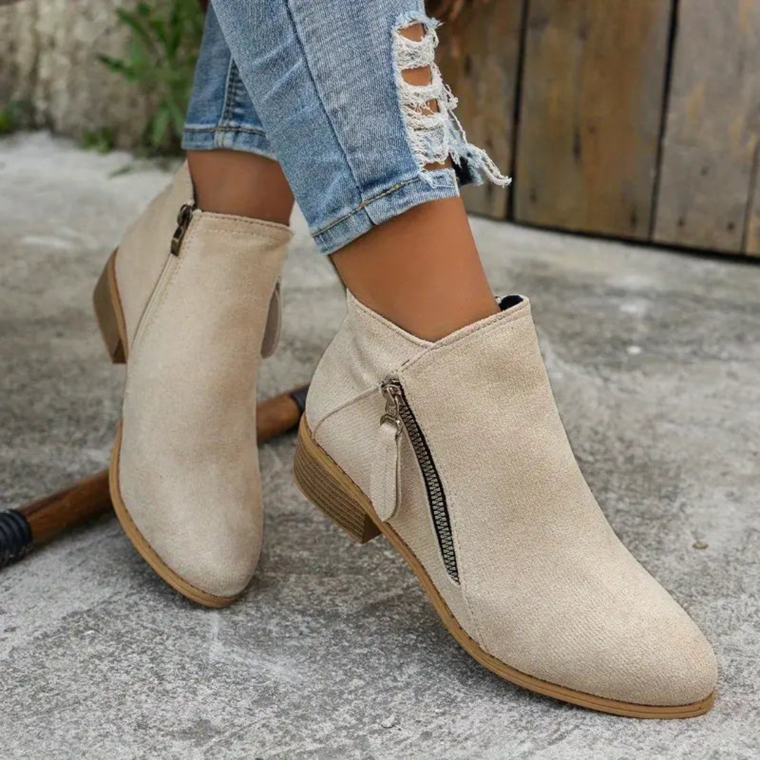 Damen Stiefeletten in Beige, seitlicher Reißverschluss, abgerundete Spitze, kombiniert mit zerrissenen Jeans. Modische Herbstschuhe für Frauen.