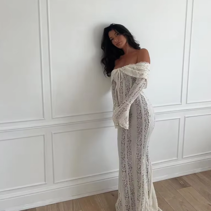 Frau in eleganter, schulterfreier Spitzenkleid vor weißer Wand. Modetrend, Abendmode, Spitzenkleid, stilvolle Damenbekleidung, elegante Kleidung.