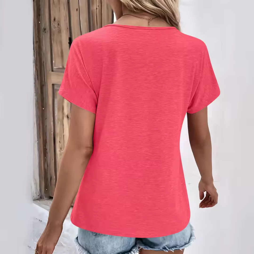 Rückansicht einer Frau in einem pinken T-Shirt und Jeansshorts vor einer Holztür. Sommermode, Freizeitkleidung, lässiger Stil.