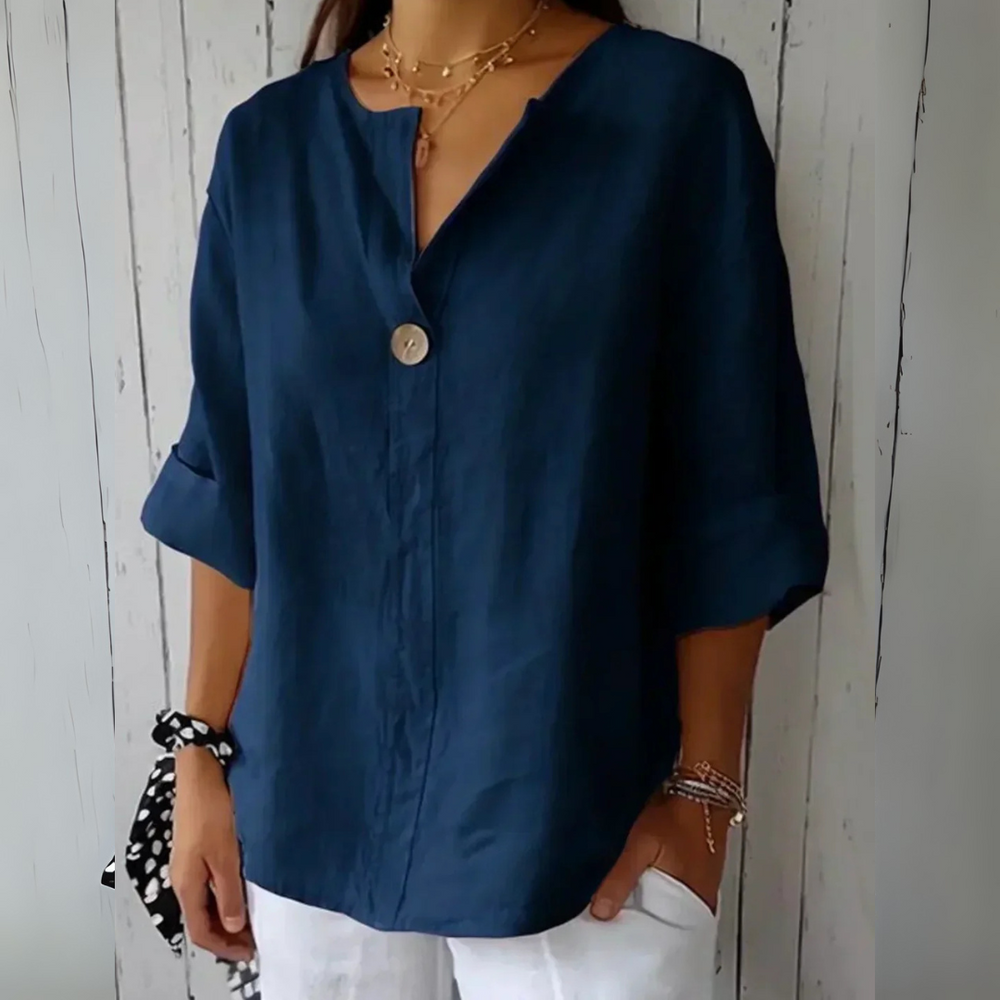 Dunkelblaue Leinenbluse mit V-Ausschnitt und Knopfdetail, kombiniert mit weißen Hosen. Modischer, lässiger Look für Damen.
