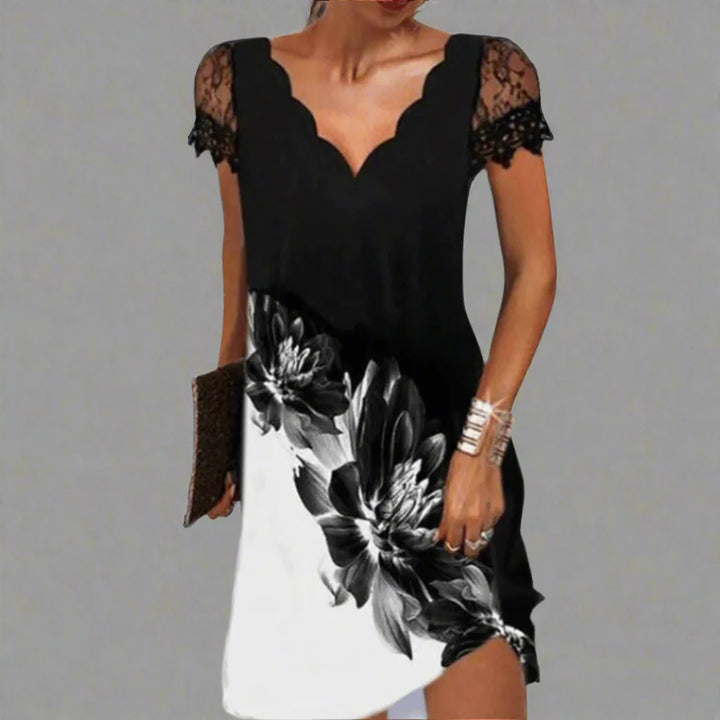 Frau in elegantem schwarz-weißem Kleid mit Blumenmuster und Spitzenärmeln, hält eine Clutch. Modetrend, Abendmode, stilvolles Design.