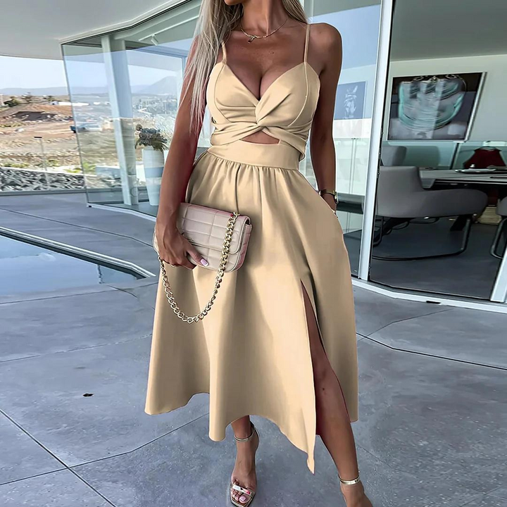 Elegantes beige Sommerkleid mit Cut-Outs und Beinschlitz, getragen von einer Frau auf einer modernen Terrasse. Perfekt für stilvolle Sommermode.